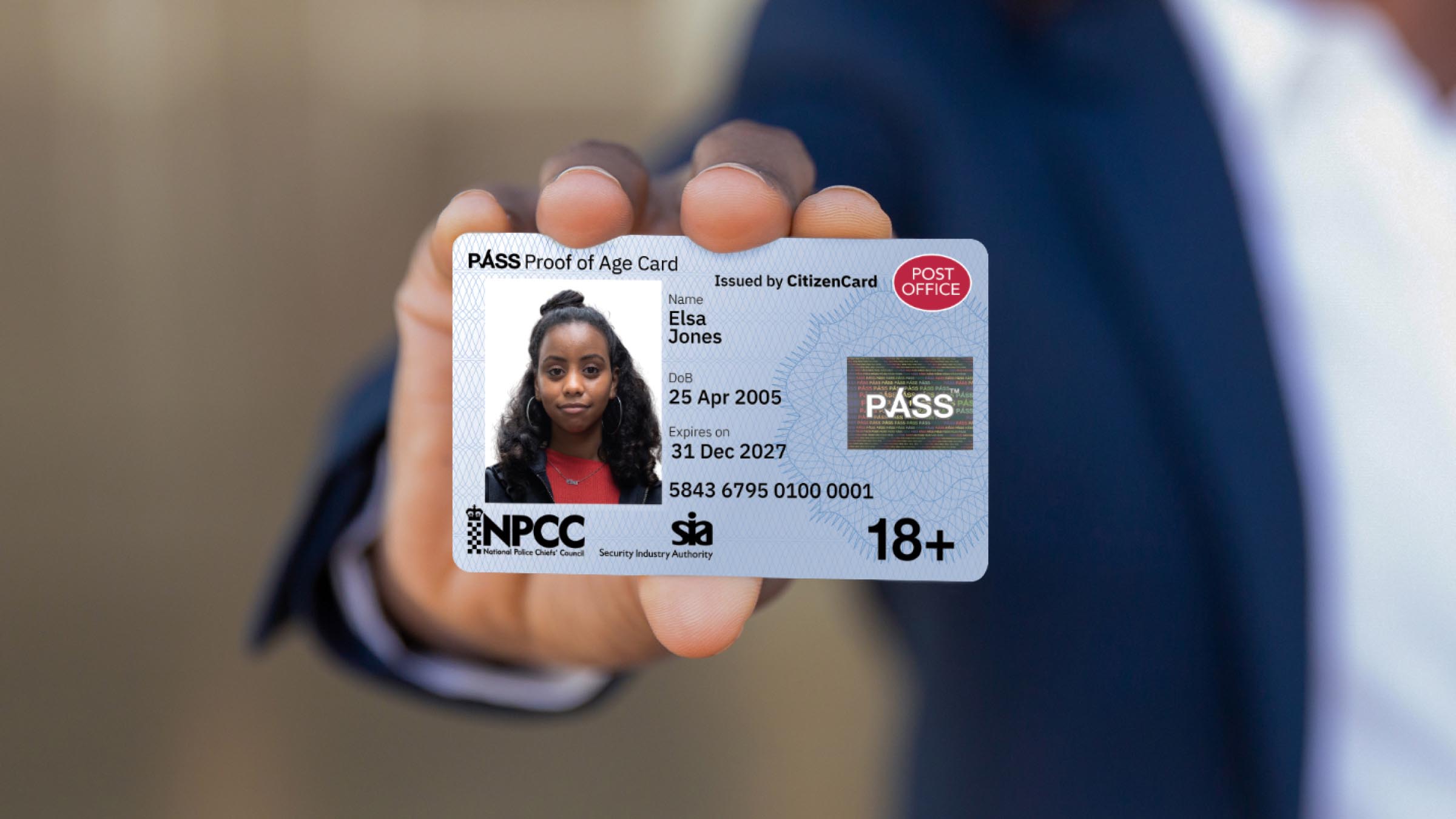 a hand holding up a post office 18 plus pass card